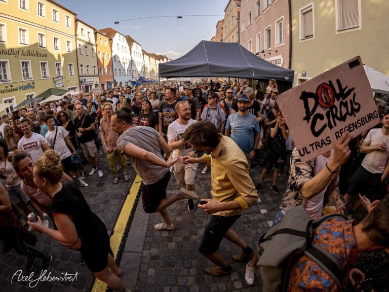 Lebhafte Menschenmenge bei einem Straßenfest in Regensburg, die tanzt und singt – © Axel Hebenstreit