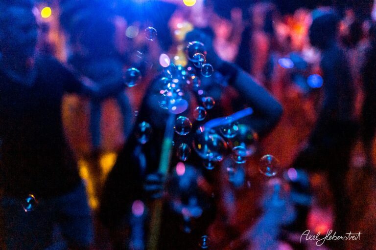 Bunte Seifenblasen schweben durch eine festliche Atmosphäre mit verschwommenen Menschen im Hintergrund – © Axel Hebenstreit