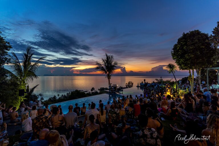 Publikum genießt Konzertatmosphäre bei Sonnenuntergang am Pool mit Meerblick auf einer tropischen Veranstaltung – © Axel Hebenstreit