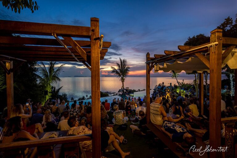 Menschen versammeln sich bei Sonnenuntergang am Meer für ein Konzert in einer entspannten Atmosphäre – © Axel Hebenstreit
