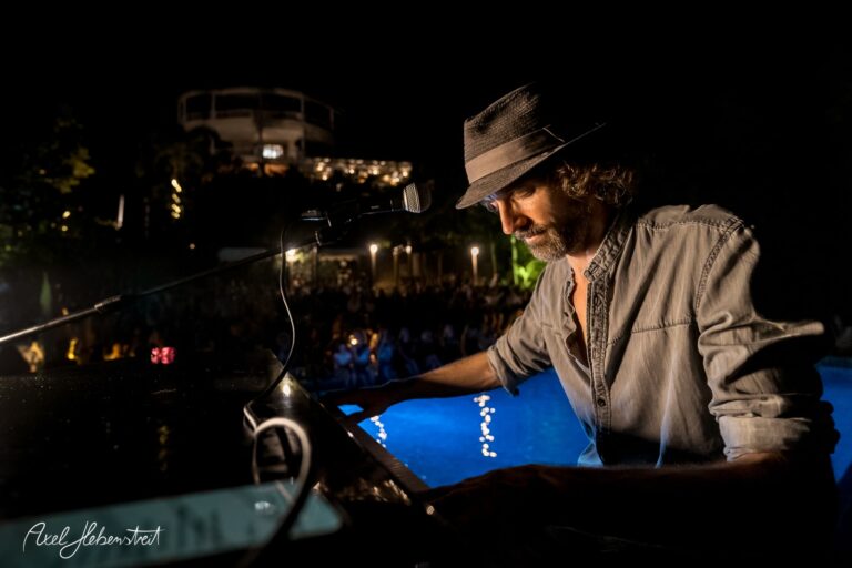 Ein Musiker spielt am Klavier bei einer stimmungsvollen Nachtveranstaltung am Pool. – © Axel Hebenstreit