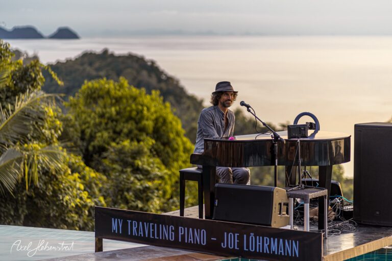 Ein Musiker spielt an einem Klavier mit Blick auf eine beeindruckende Landschaft am Meer. – © Axel Hebenstreit