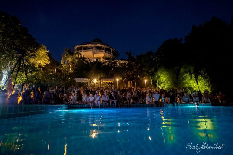 Ein Publikum sitzt am Pool und genießt ein nächtliches Konzert unter freiem Himmel – © Axel Hebenstreit