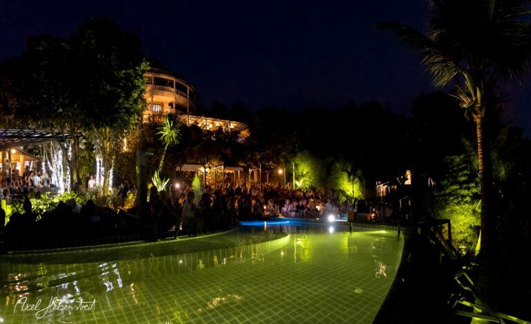 Ein stimmungsvolles Konzert am Pool, beleuchtet von Lichtern, umgeben von einer begeisterten Menge inmitten der Natur – © Axel Hebenstreit