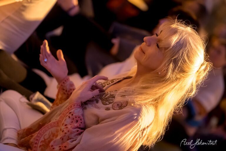 Eine Frau mit langen, blonden Haaren sitzt in entspannter Haltung und genießt eine meditative Atmosphäre – © Axel Hebenstreit
