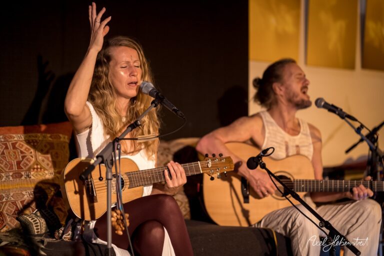 Musiker in einem intimen Konzert, singen und spielen akustische Gitarre, vereint in emotionaler Atmosphäre. – © Axel Hebenstreit