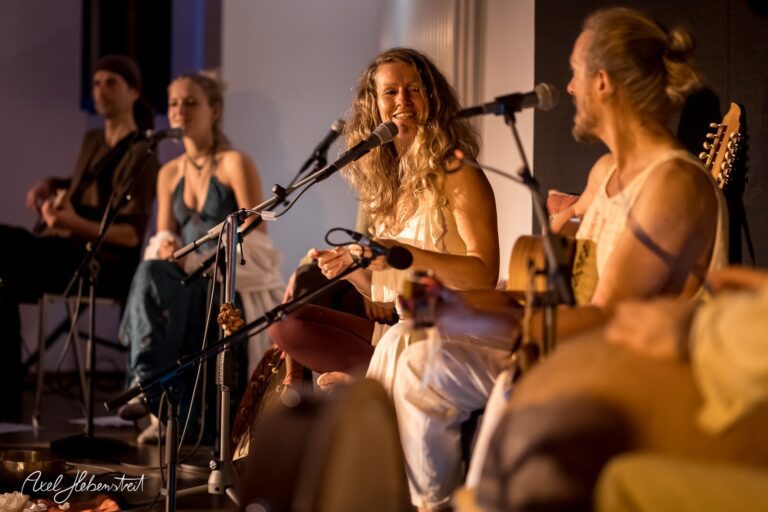 Musiker spielen miteinander und teilen fröhliche Momente während eines Konzerts in einer intimen Atmosphäre – © Axel Hebenstreit