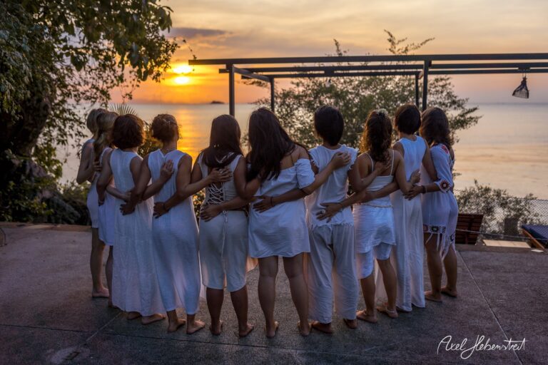 Frauen in weißen Kleidern stehen bei Sonnenuntergang am Wasser und genießen den Moment in der Natur – © Axel Hebenstreit