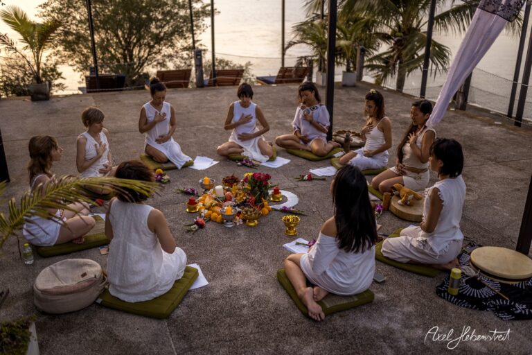 Eine Gruppe von Frauen in weißen Gewändern meditiert um einen rituellen Altar am Meer – © Axel Hebenstreit
