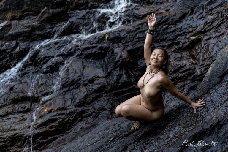 Eine Person posiert an einem Wasserfall auf einem Felsen und vermittelt ein Gefühl von Kraft und Freiheit – © Axel Hebenstreit