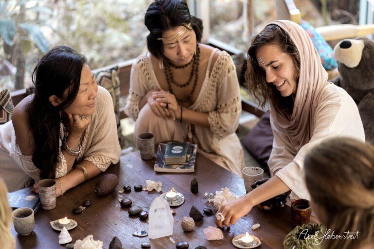 Drei Frauen in entspannter Atmosphäre um einen Tisch mit Kristallen, Kerzen und spirituellen Gegenständen – © Axel Hebenstreit