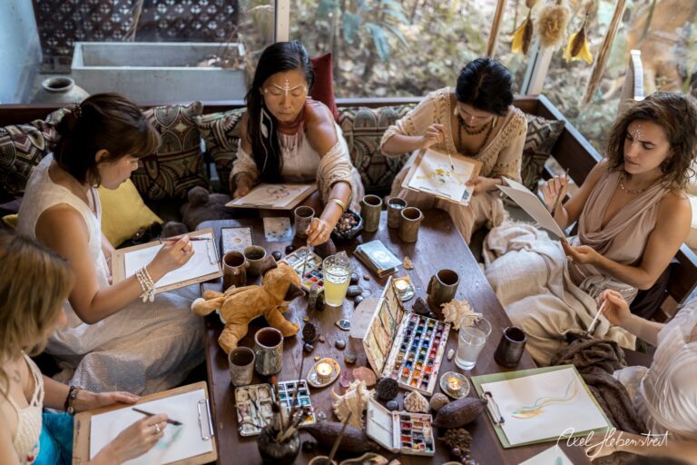 Eine Gruppe von Frauen sitzt an einem Tisch und malt kreativ, umgeben von naturverbundener, entspannter Atmosphäre – © Axel Hebenstreit