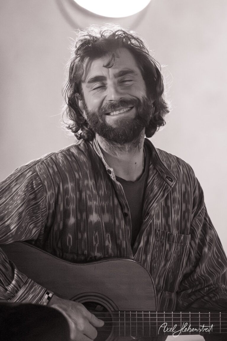 Lächelnder Musiker mit Gitarre in entspannter Atmosphäre – © Axel Hebenstreit