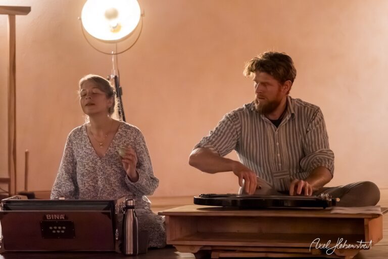 Musikerin und Musiker in einem meditativen Moment während einer Performance in einem stimmungsvollen Raum – © Axel Hebenstreit