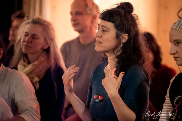 Eine Frau mit geschlossenen Augen und ausdrucksstarker Gestik in einer meditativen Atmosphäre – © Axel Hebenstreit