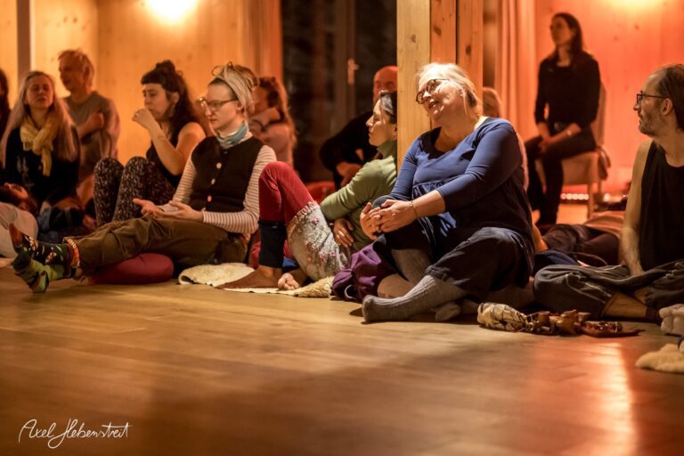 Eine Gruppe von Menschen sitzt entspannt im Raum und genießt eine gemeinsame Yoga-Session – © Axel Hebenstreit