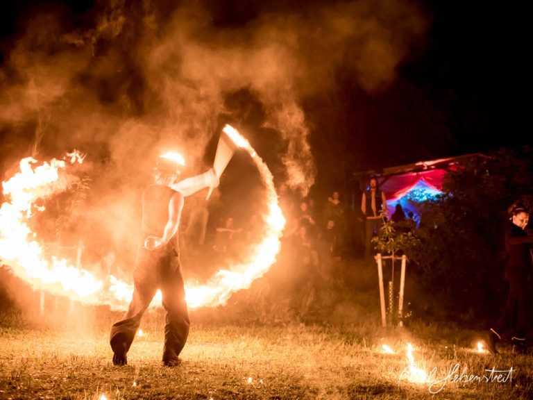 Ein Feuerartist kreiert faszinierende Lichtspiralen in einer nächtlichen Festivalatmosphäre. – © Axel Hebenstreit