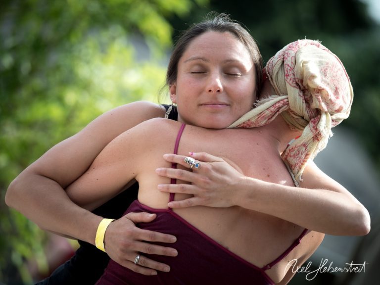 Zwei Frauen umarmen sich innig in einer entspannten Atmosphäre während eines Festivals im Freien. – © Axel Hebenstreit