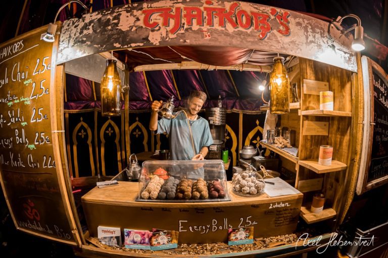 Ein freundlicher Verkäufer bietet an einem festlichen Stand frisch zubereitete Energieball-Snacks an. – © Axel Hebenstreit