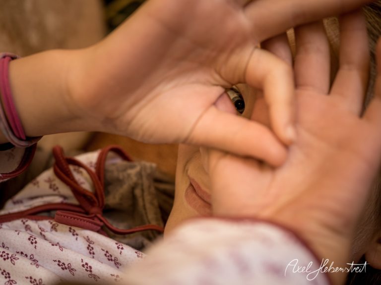 Ein Kind schaut durch ein Loch, das mit Händen geformt wurde, und vermittelt eine verträumte, neugierige Stimmung. – © Axel Hebenstreit