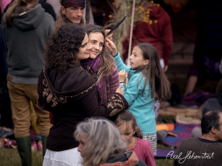Zwei Frauen umarmen sich lächelnd auf einem Festival, umgeben von lässiger, fröhlicher Menschenmenge. – © Axel Hebenstreit