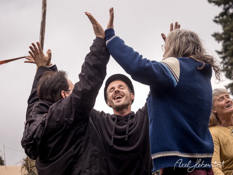 Eine Gruppe von Menschen feiert fröhlich und begeistert im Freien, umgeben von Natur – © Axel Hebenstreit
