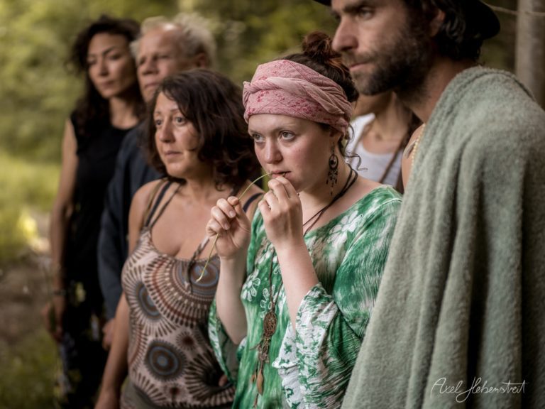 Gruppe von Menschen in bohemischem Stil steht nachdenklich im grünen Wald zusammen – © Axel Hebenstreit