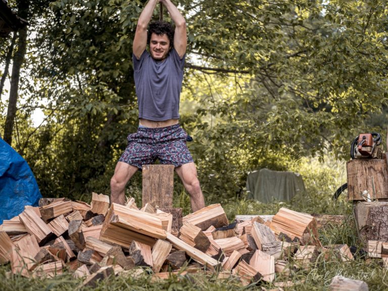 Mann springt auf Holzstapel in waldiger Umgebung während Outdoor-Training – © Axel Hebenstreit