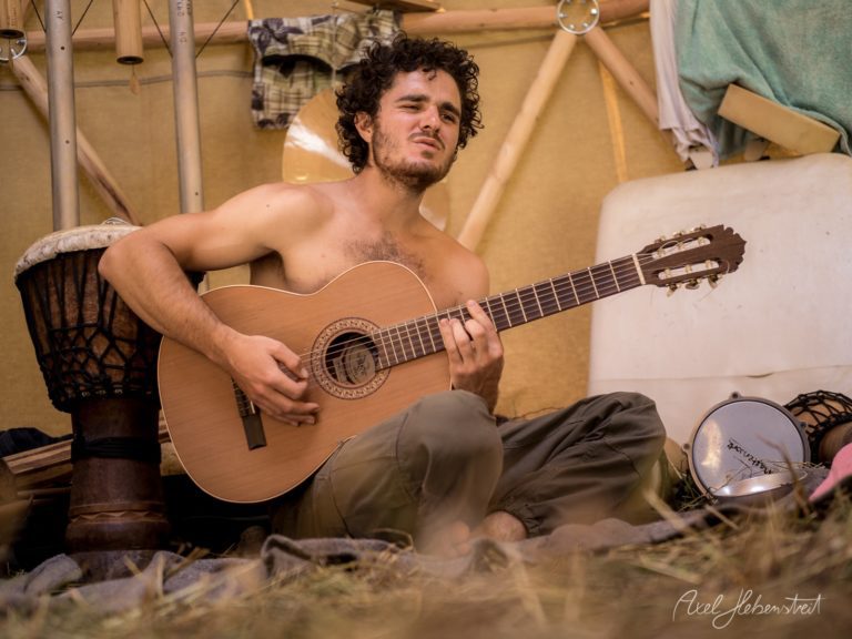 Barfüßiger Musiker spielt konzentriert Klassikgitarre in einem Zelt beim Festival – © Axel Hebenstreit