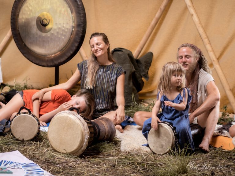 Familie musiziert zusammen mit Trommeln in einem Tipi während eines Workshops in naturnaher Umgebung – © Axel Hebenstreit