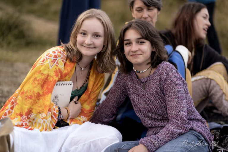 Zwei junge Frauen lächeln freundlich in entspannter Atmosphäre während eines Festivals im Freien. – © Axel Hebenstreit