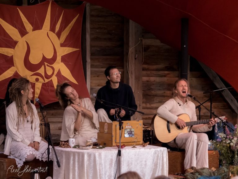 Musiker in entspannter Atmosphäre bei einem Konzert, umgeben von Natur, mit Akustikgitarre und spirituellen Einflüssen – © Axel Hebenstreit