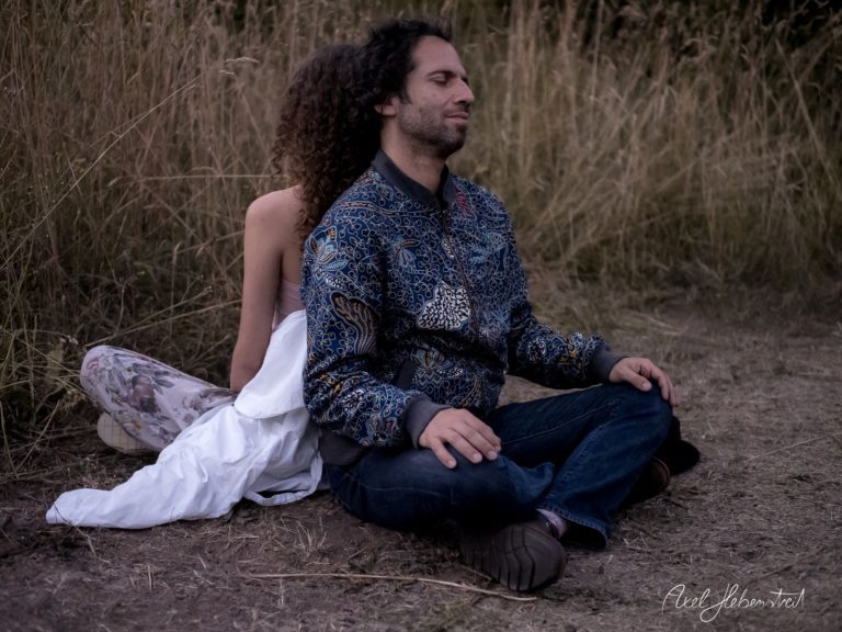 Meditative Pose eines Pärchens in der Natur, umgeben von hohen Gräsern – © Axel Hebenstreit