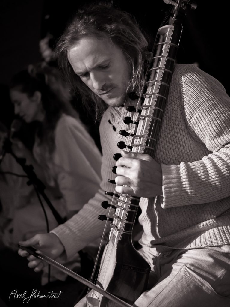 Ein Musiker spielt leidenschaftlich ein traditionelles Instrument während eines Konzerts in einer entspannten Atmosphäre – © Axel Hebenstreit