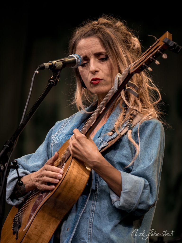 Eine Sängerin mit Gitarre in entspannter Atmosphäre während eines Konzerts – © Axel Hebenstreit