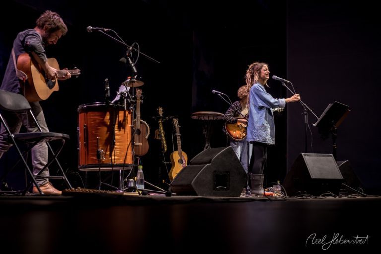 Eine Sängerin performt auf der Bühne, begleitet von einem Gitarristen und einem Percussionisten – © Axel Hebenstreit