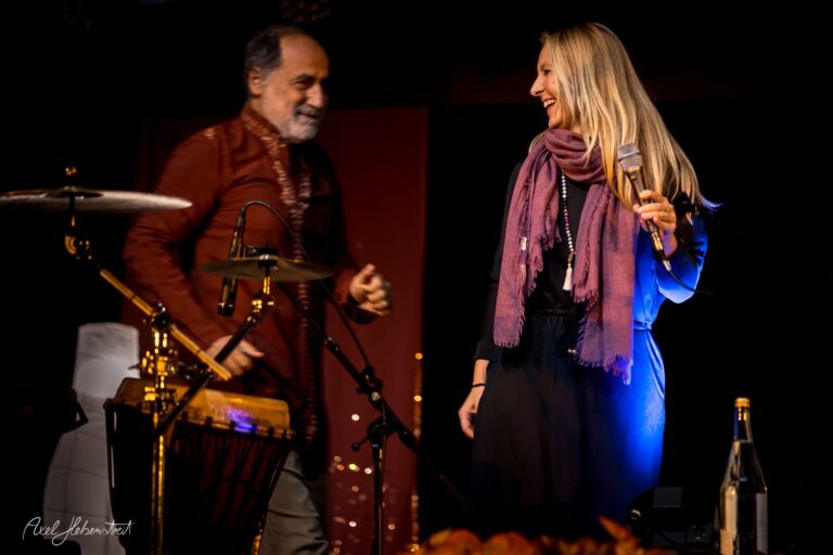 Ein Musiker und eine Sängerin lächeln sich während eines Auftritts auf der Bühne an – © Axel Hebenstreit.