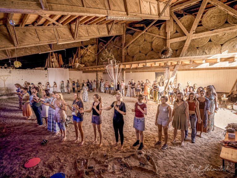 Große Gruppe von Frauen beim gemeinsamen Tanzen und Feiern in einer rustikalen Scheune mit Heuballen – © Axel Hebenstreit