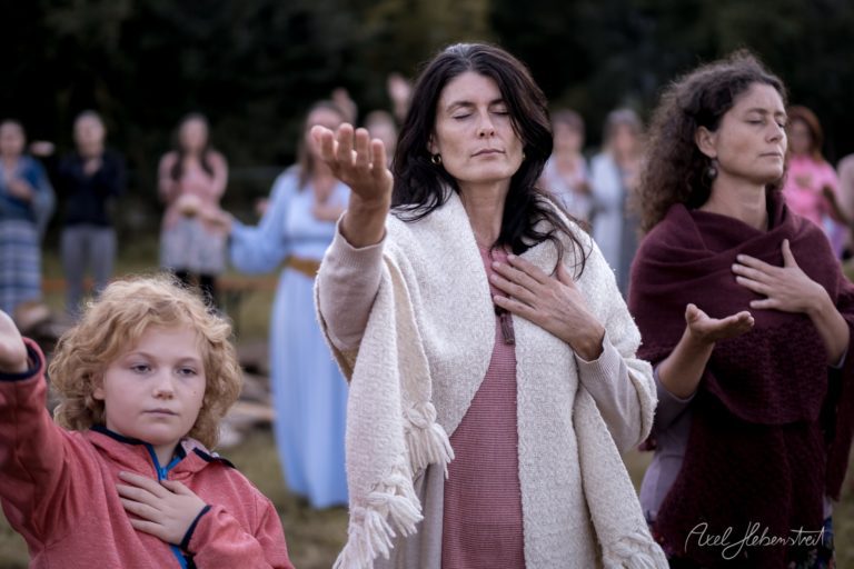Frau mit Kind bei spiritueller Zeremonie im Freien mit erhobenen Händen in meditativer Haltung – © Axel Hebenstreit