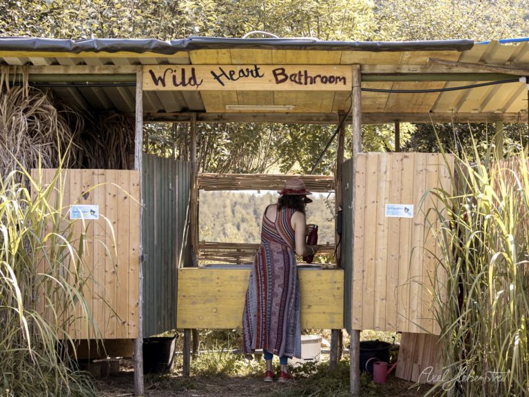 Frau am Wild Heart Bathroom Waschplatz in naturbelassener Umgebung mit Schilfdach und Holzverkleidung – © Axel Hebenstreit