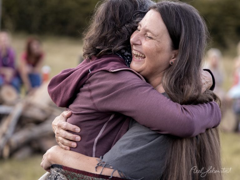 Zwei Frauen umarmen sich herzlich und lachend auf einem Fest im Freien – © Axel Hebenstreit
