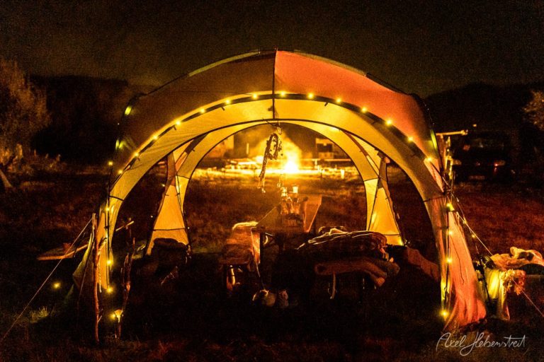 Illuminiertes Festivalzelt bei Nacht mit Besuchern und warmem Licht in der Dunkelheit – © Axel Hebenstreit
