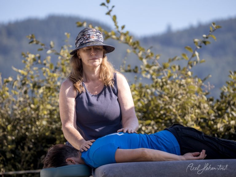 Yogalehrerin führt Massage an einer Frau in bergiger Naturlandschaft durch – © Axel Hebenstreit