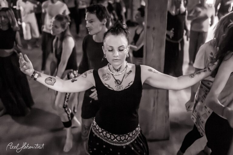 Tanzende Frau mit Tattoos und geschlossenen Augen inmitten einer Festivalatmosphäre – © Axel Hebenstreit
