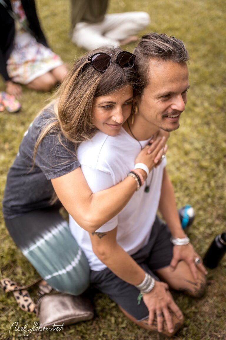 Ein Paar sitzt umarmt auf einer Wiese und genießt den Moment der Zweisamkeit bei einem Festival – © Axel Hebenstreit.