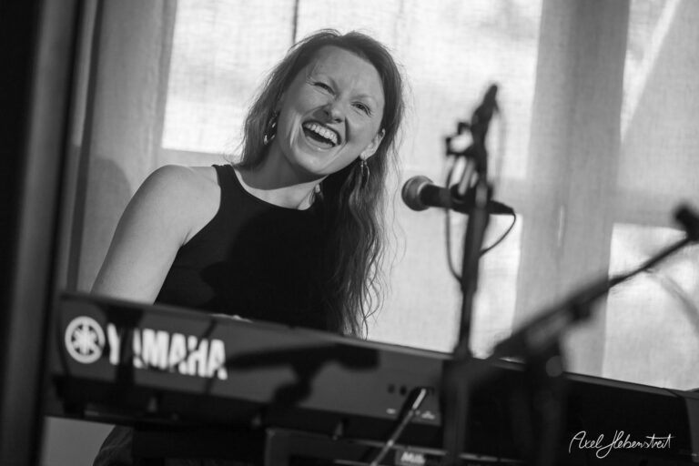 Lachende Musikerin an einem Yamaha-Keyboard während einer Live-Performance in hellem Innenraum
