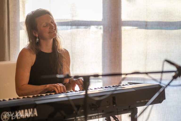 Frau spielt konzentriert Keyboard in lichtdurchflutetem Raum während einer Musiksession.