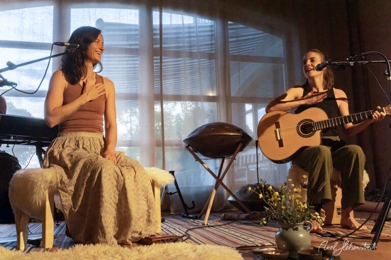 Zwei Musikerinnen bei einer intimen Yoga- und Musiksession in einem lichtdurchfluteten Raum mit Hangdrum.