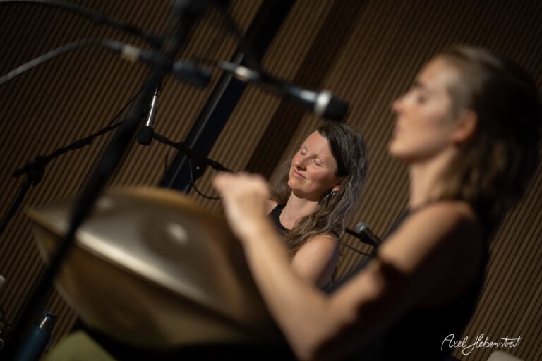 Zwei Frauen in entspannter Yoga-Pose in einem Studio mit warmer Holzatmosphäre