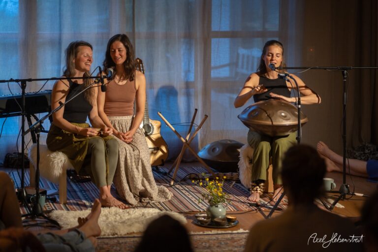 Drei Musikerinnen bei einem intimen Handpan-Konzert in stimmungsvollem Ambiente mit blauer Beleuchtung.